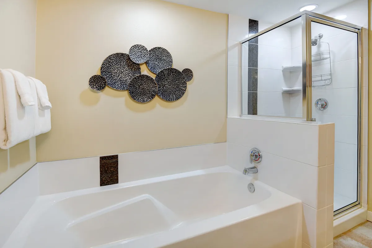 A tranquil bathroom featuring a bathtub and enclosed shower, accented by tasteful wall art. The setting is refined and spa-like, perfect for indulging in restorative soaks and self-care routines.